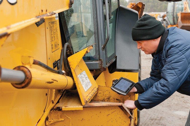 Driver performing a pre-start walkaround inspection on a heavy vehicle, checking tyres and wheel condition before departure